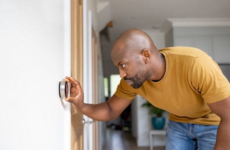 African American man adjusting the temperature on the smart thermostat of his house