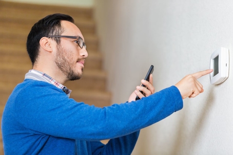 Hispanic man adjusting thermostat